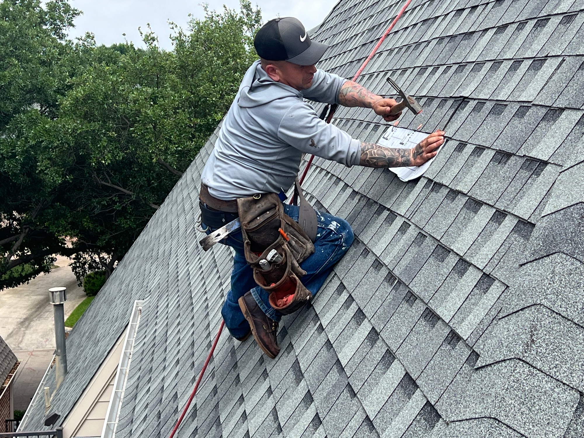 Roofer installing shingles on a steep residential roof