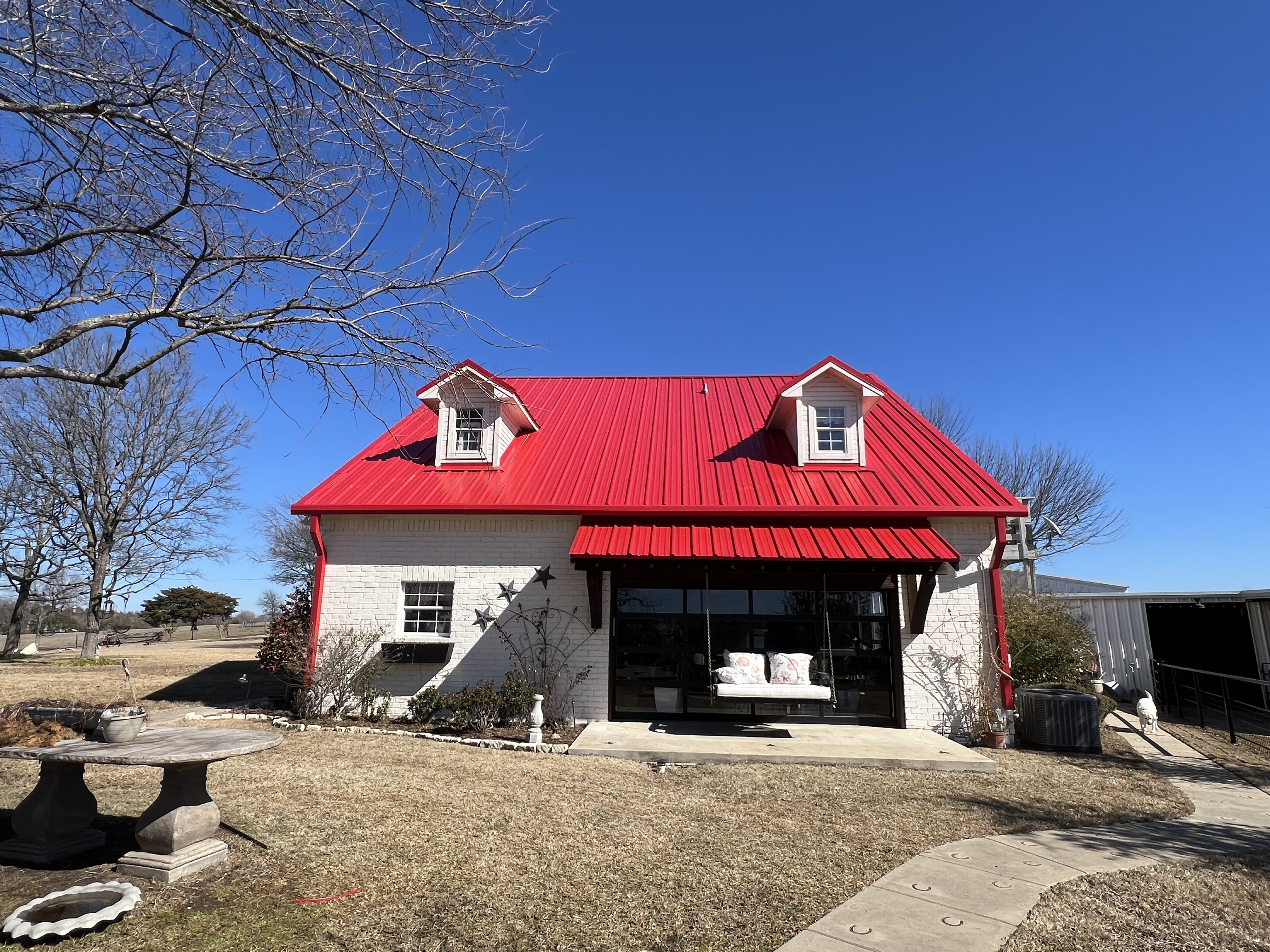 House with bright red metal roof completed by New Era Roofing